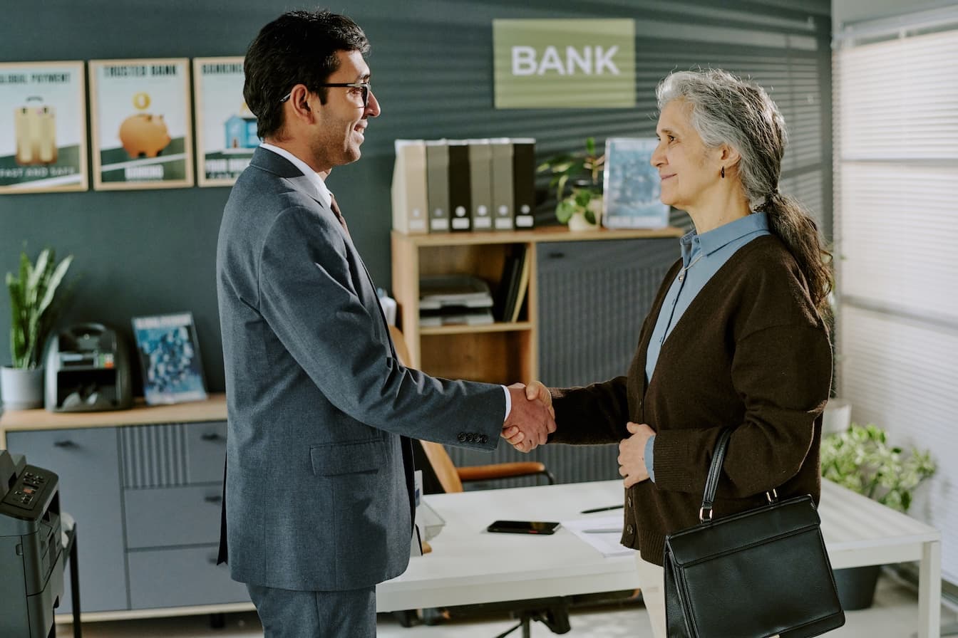 Un conseiller bancaire serre la main à une cliente pour un prêt trésorerie entreprise.